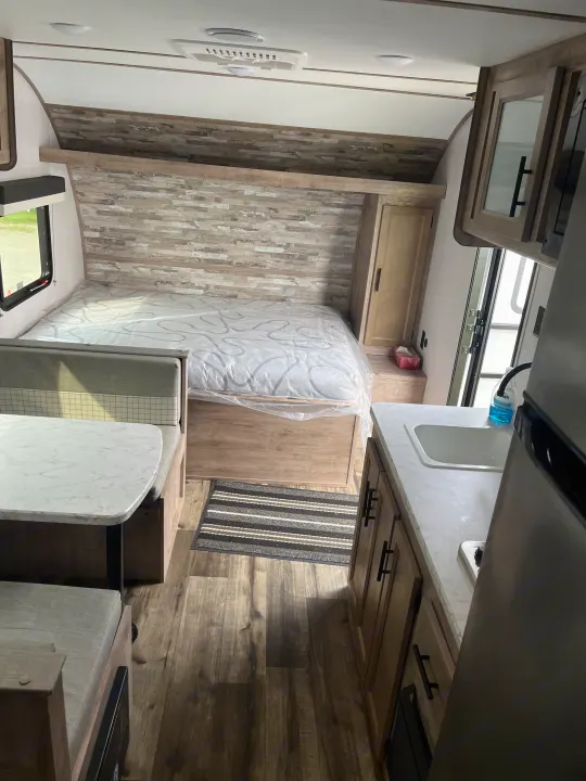 Step inside this rv rental: A modern interior with a bed, dinette, kitchen, and wood-look flooring.. Gulf Stream grand river 2024