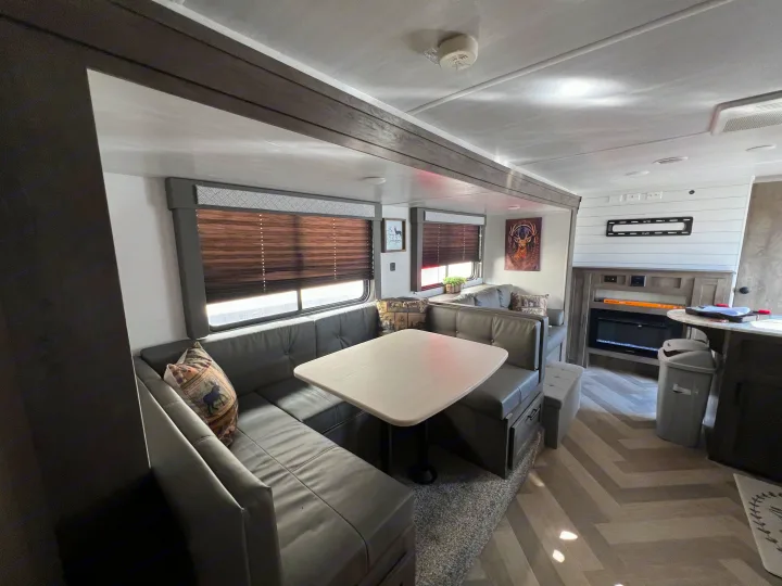 Spacious RV rental interior with a cozy dinette, fireplace, and modern decor featuring a deer motif.. Forest River Wildwood X-Lite 2020