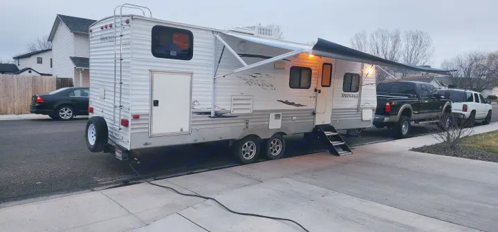 This RV rental, a Springdale travel trailer, is parked and set up with an awning and lights, waiting for a camping trip.. Keystone Springdale 2010