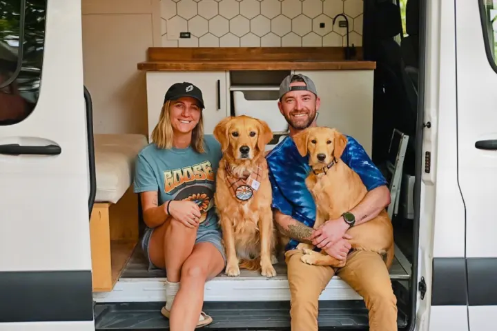 A couple and their two Golden Retrievers smile from inside their pet-friendly RV rental.. Mercedes-Benz Sprinter 2021