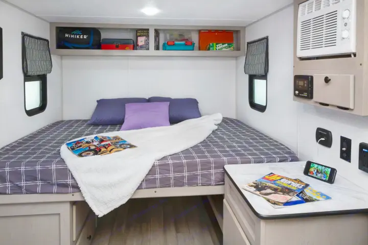 Cozy bedroom with smart storage, heat, AC, and functional nightstand with charging station. . Forest River Viking 12000 2024