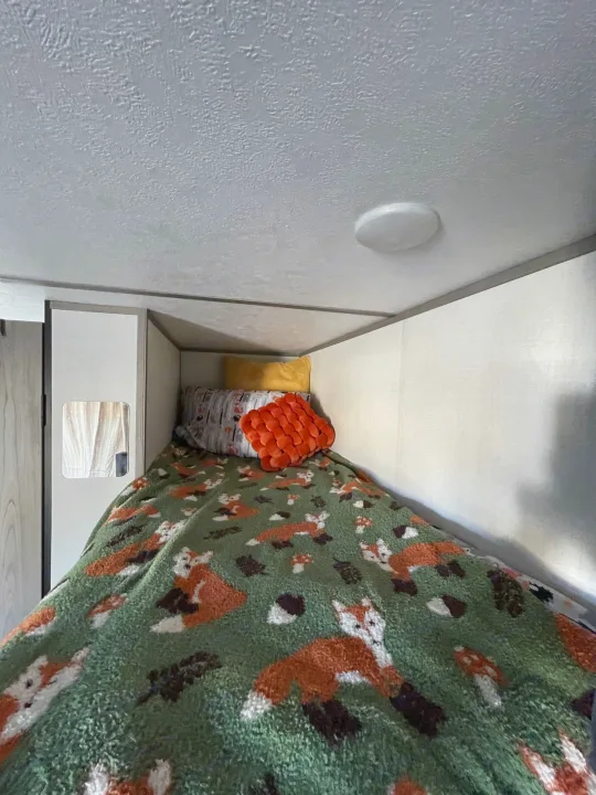Cozy RV rental bunk bed with fox blanket and textured ceiling.. Keystone RV COLEMAN LANTERN LT 17B 2024