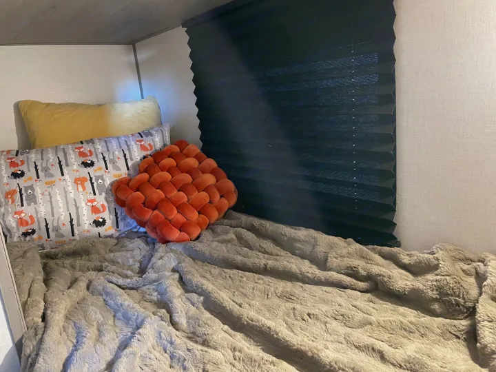 Cozy RV rental bunk bed setup with forest animal pillows, a soft blanket, and a privacy shade for comfy travels.. Keystone RV COLEMAN LANTERN LT 17B 2024