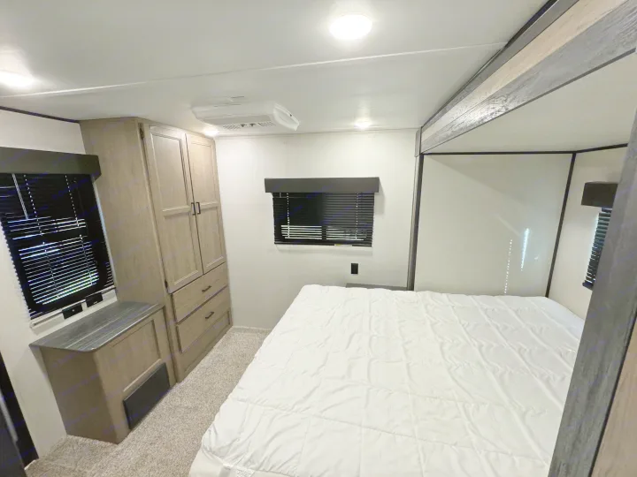 Discover this inviting RV rental bedroom. It features a comfortable bed, built-in storage, and an overhead AC unit for your travels.. Keystone Hideout 2021
