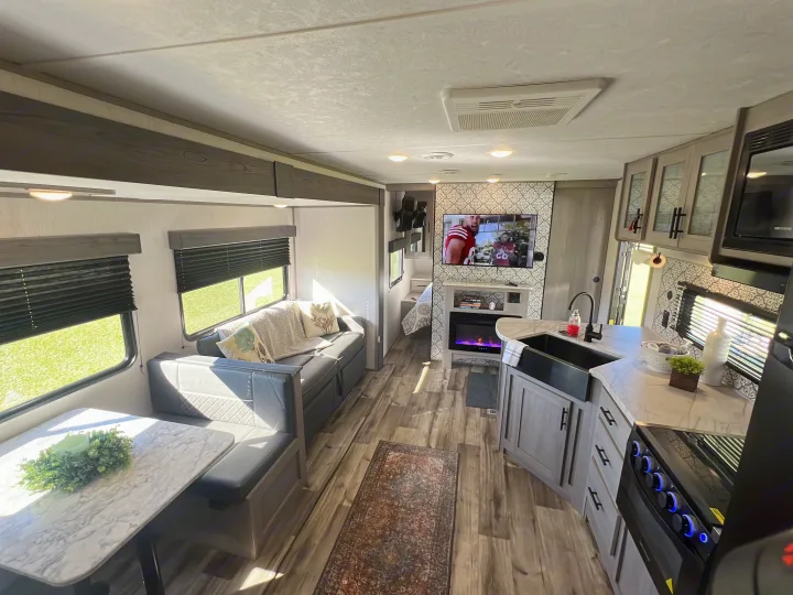 This RV rental showcases a bright, modern camper interior with kitchen, dining, living room, and a bedroom beyond.. Dutchmen Coleman Lantern 2023