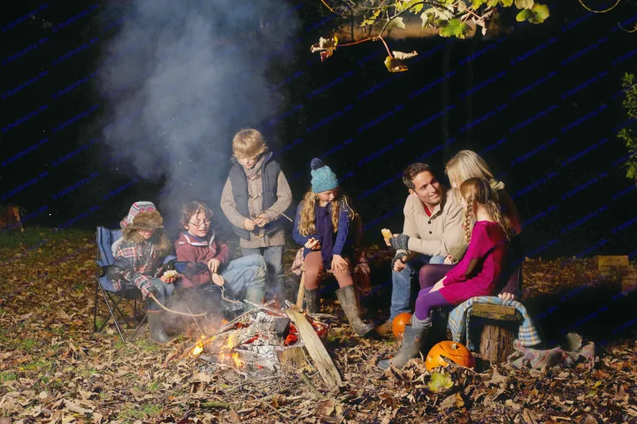 Cozy campfire fun after an RV rental adventure. Family & friends enjoy roasting snacks by the fire at night.. Dutchmen Coleman Lantern 2023