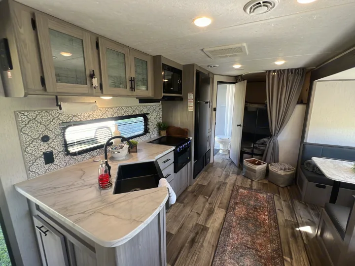 Inside a comfortable RV rental: kitchen, dining, bunks, and bathroom. Ready for your next adventure!. Dutchmen Coleman Lantern 2023