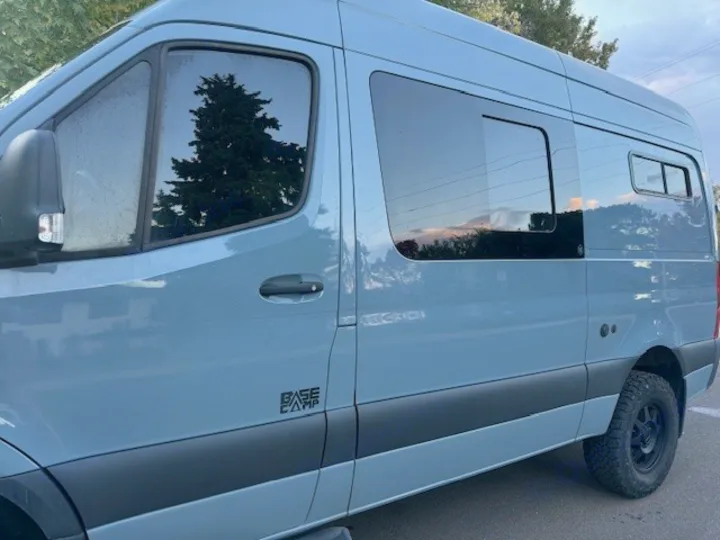 Light blue custom Sprinter camper van for adventure RV rental, with tinted windows and all-terrain tires.. Mercedes-Benz Sprinter 2021