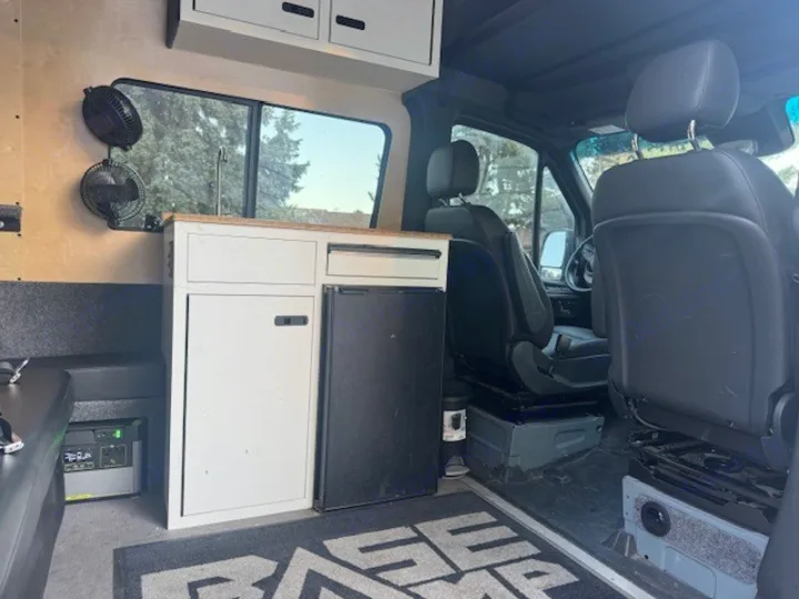 RV rental interior shows a compact kitchen with fridge & sink, fans, and a Goal Zero power station for mobile living.. Mercedes-Benz Sprinter 2021
