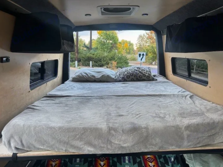RV rental interior: a comfy bed with pillows, featuring a scenic view out the rear window. Ready for adventure.. Mercedes-Benz Sprinter 2021