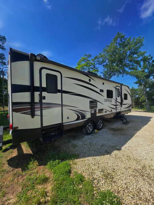 Enjoying the sunny weather with a Denali Lite travel trailer, a great option for an RV rental parked at a serene campsite.. Denali Lite 2015