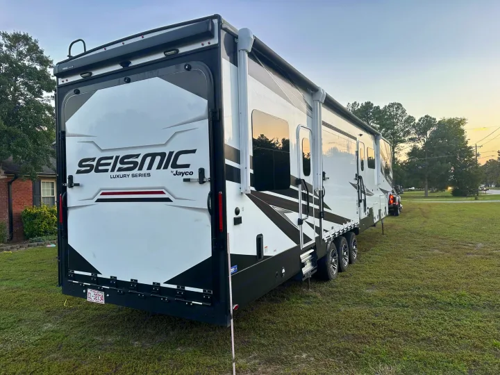 Luxury white & black Jayco Seismic toy hauler RV rental on grass. Perfect for travel & outdoor excursions.. Jayco Seismic 2023