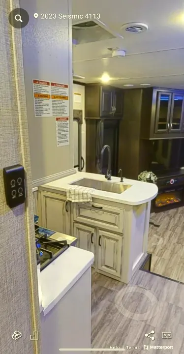Step inside this 2023 Seismic 4113 RV rental, featuring a full kitchen with an island, sink, stovetop, and cozy living area.. Jayco Seismic 2023