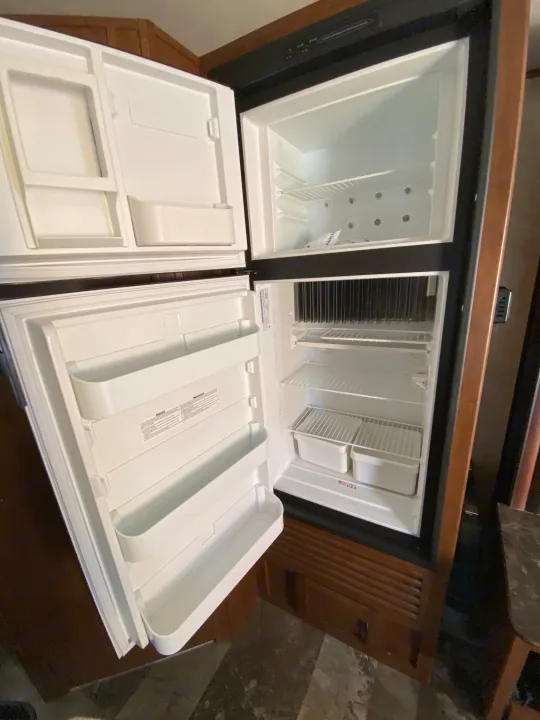 Inside a clean, empty RV refrigerator/freezer unit, ideal for an RV rental. Features wire shelves & door bins.. Jayco Jay Feather 7 2016