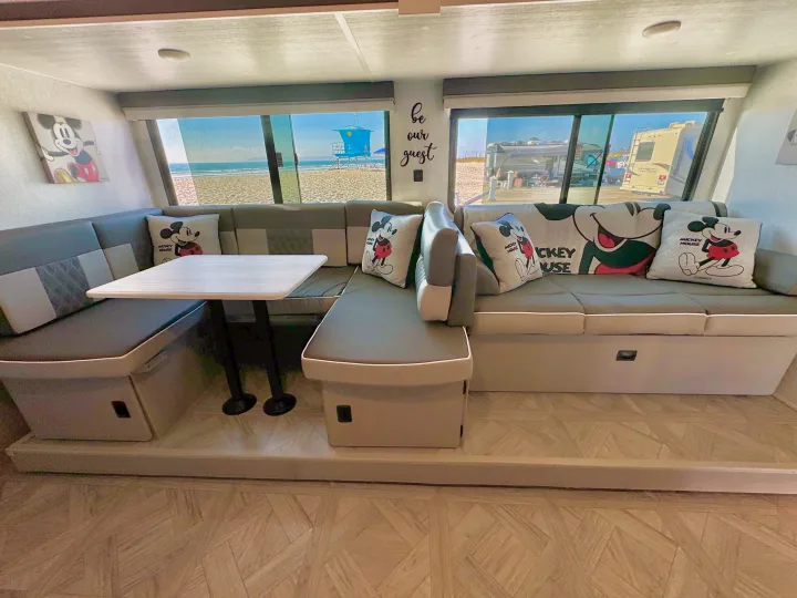 RV rental: Step inside this cozy Mickey Mouse-themed RV interior, offering comfortable seating and direct beach views.. Forest River Wildwood 2024