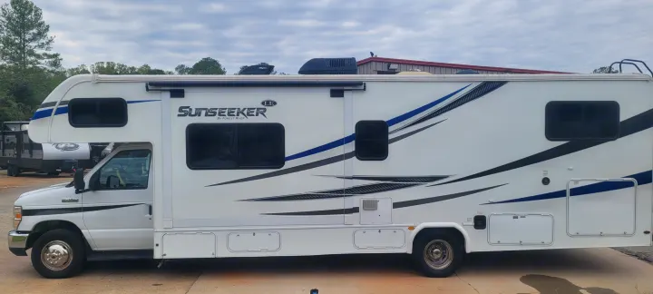 White Forest River Sunseeker Class C RV rental with blue/black graphics, parked outdoors.. Forest River Sunseeker LE 2020
