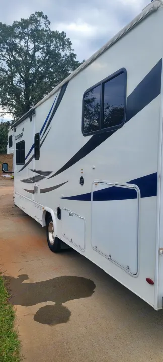 A white Sunseeker rv rental, perfect for your next road trip, parked with its storage compartments visible.. Forest River Sunseeker LE 2020