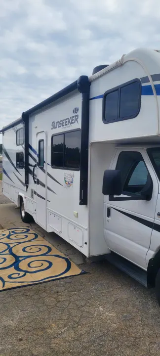 This white Sunseeker Class C RV rental, parked with an outdoor rug, is ready for adventure.. Forest River Sunseeker LE 2020