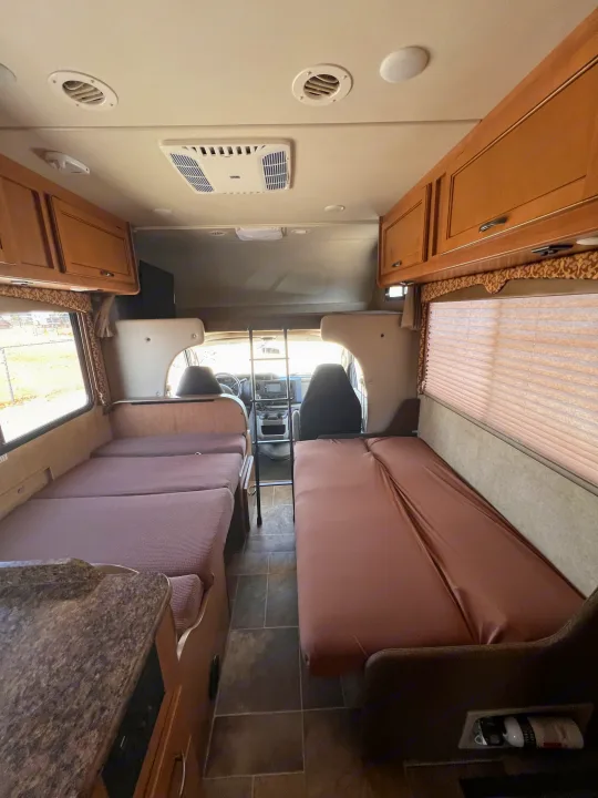 View inside an RV rental showing the comfortable living area with dual bench beds, a kitchen counter, and the cockpit.. Thor Motor Coach Freedom Elite 2017