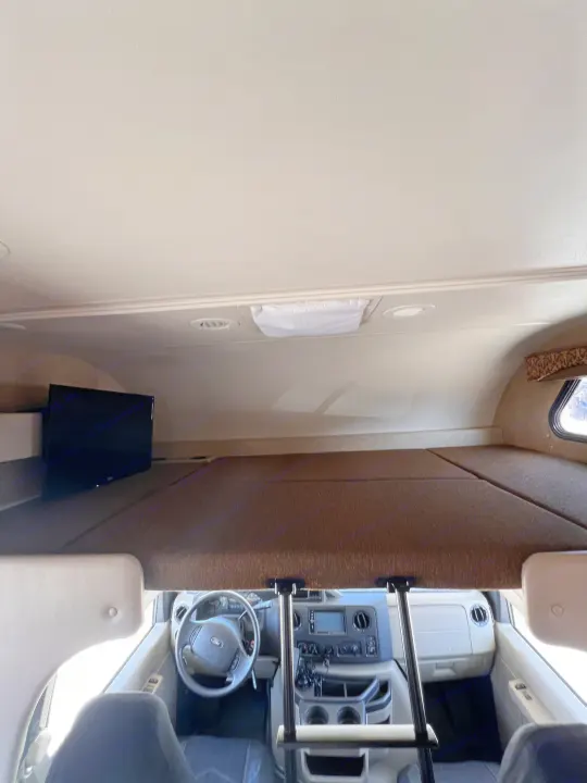 Overhead bunk with TV & front cockpit view inside a spacious RV rental. Ready for adventure.. Thor Motor Coach Freedom Elite 2017