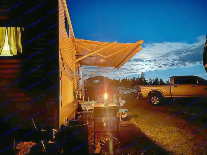 Night at an RV rental campsite: cozy setup under awning with bright lantern, full moon, and truck nearby.. Crossroads RV Zinger 2016