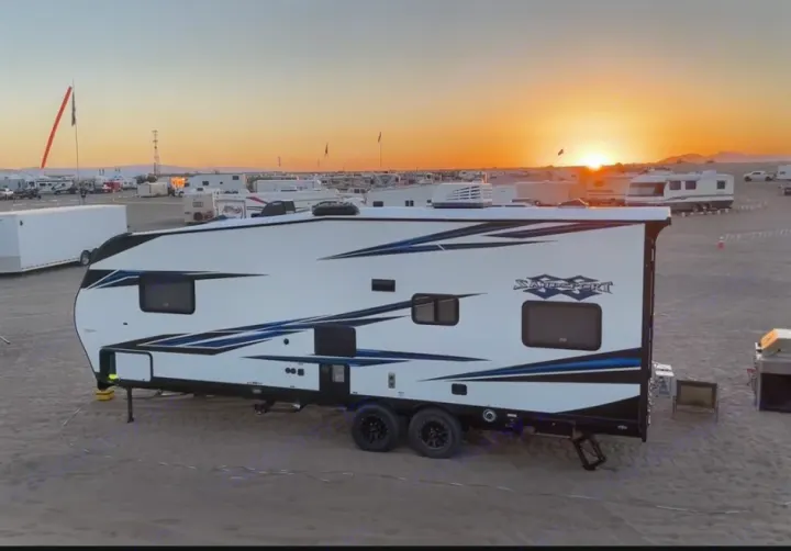 White Savage Sport RV rental at sunset in a vast desert camp, surrounded by many other recreational vehicles.. Pacific Coachworks Sandsport 2022