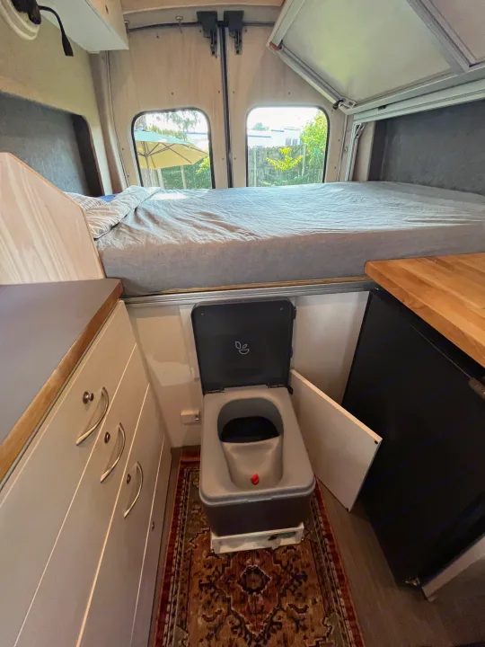 Inside this RV rental: a comfy bed, modern composting toilet, and efficient kitchen/storage solutions.. Custom Built Transit 2017