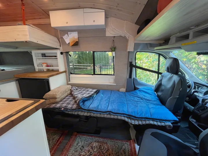 Spacious camper van interior, perfect for an RV rental. Features a cozy bed, mini-kitchen, and clever storage.. Custom Built Transit 2017