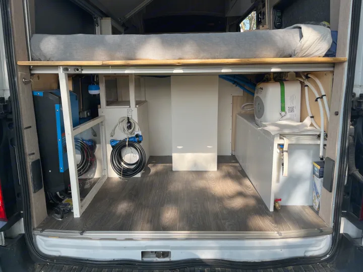 RV rental utility space: Organized bed, power, & water systems in a clean camper van interior.. Custom Built Transit 2017
