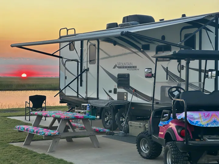 Waterfront RV rental setup at sunset with a golf cart and picnic area, offering serene outdoor living.. Outdoors RV Timber Ridge 2020