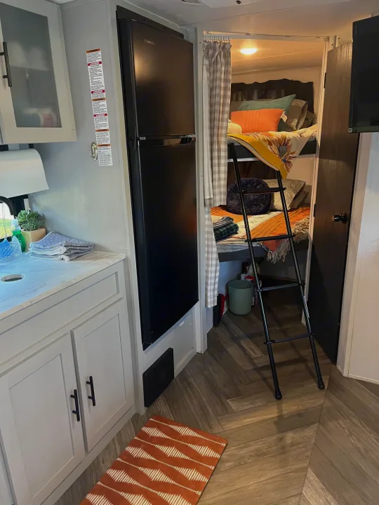 Spacious RV rental interior: modern kitchen, refrigerator, and cozy bunk beds with ladder. Ready for your family adventures!. Forest River Wildwood FSX 2021