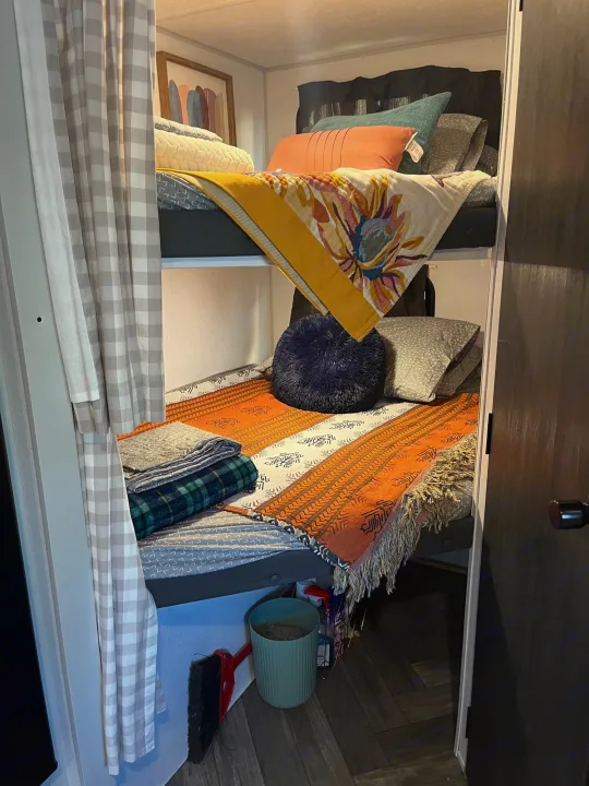This RV rental features stacked bunk beds with colorful, inviting bedding and a privacy curtain, ideal for guests.. Forest River Wildwood FSX 2021