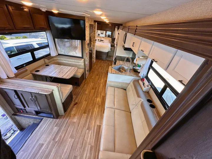 Spacious RV rental interior with full kitchen, comfortable sofa, dinette, and private rear bedroom.. Thor A.C.E. 2018