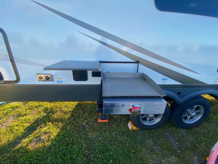 This RV rental features an outdoor griddle setup. The Titan Flame cooktop is attached, ready for delicious camp meals.. Forest River Rockwood Signature 2024
