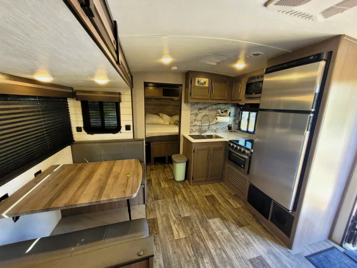Spacious RV rental interior with a fully-equipped kitchen, dining area, and a glimpse of the cozy bedroom.. Crossroads Sunset Trail Super Lite 2022