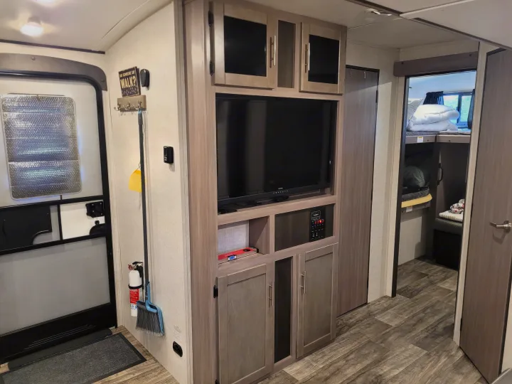Spacious RV rental interior featuring a TV entertainment unit, main entry door, and a cozy bunk bed area for comfort.. Crossroads Sunset Trail Super Lite 2022