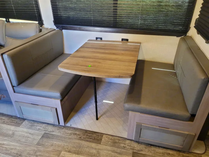 Modern RV rental dinette with grey upholstered bench seats, wood table, wall mounts, and under-seat storage.. Crossroads Sunset Trail Super Lite 2022