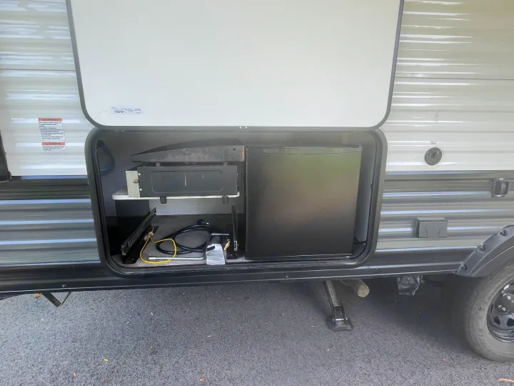 RV rental outdoor kitchen shows a built-in griddle, mini-fridge, and tools in a storage compartment.. Forest River Wildwood X-Lite 2022