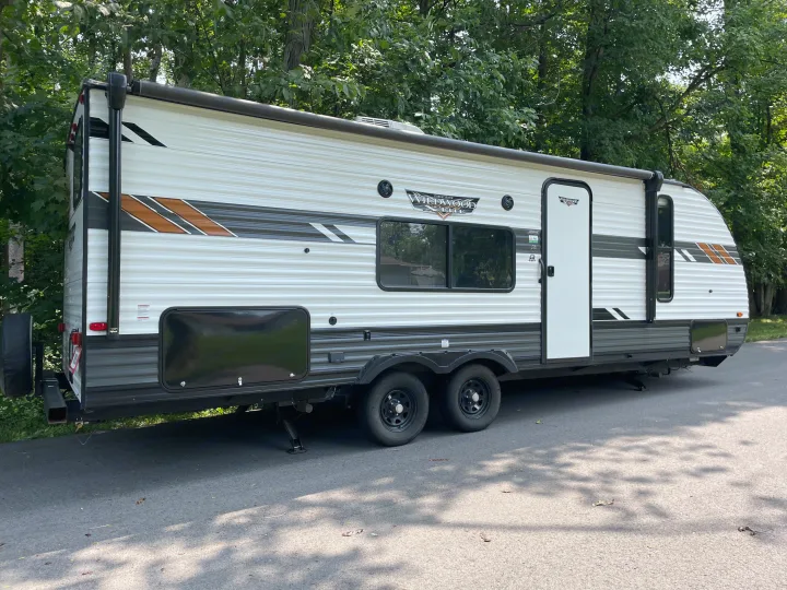 Bright, modern white & grey travel trailer, a Forest River Wildwood Lite RV, parked outdoors. Great for an RV rental vacation.. Forest River Wildwood X-Lite 2022