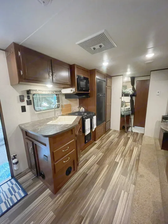 Spacious RV rental interior featuring a full kitchen, wood-look flooring, and bunk beds.. Jayco Jay Flight SLX 2017