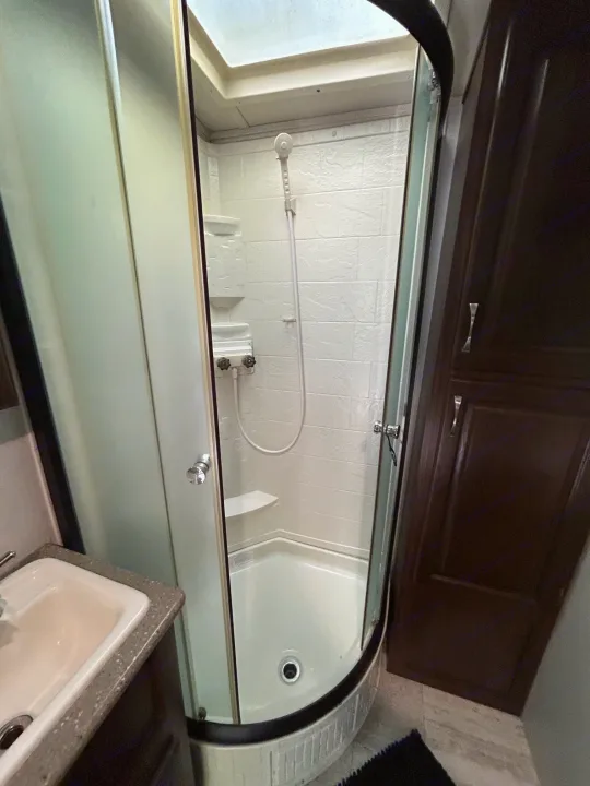 Interior of an RV rental: a compact bathroom featuring a curved glass shower and a sink area.. Palomino Solaire 2018