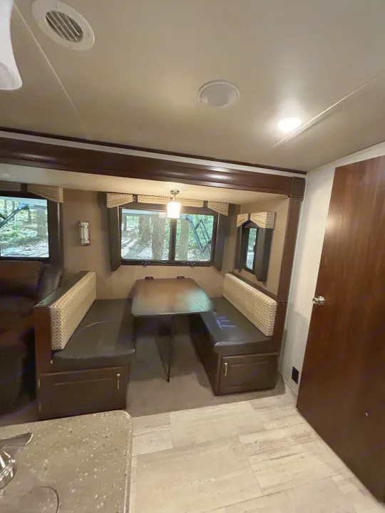 This RV rental interior features a cozy dinette with booth seating and a table, ideal for dining and relaxing.. Palomino Solaire 2018