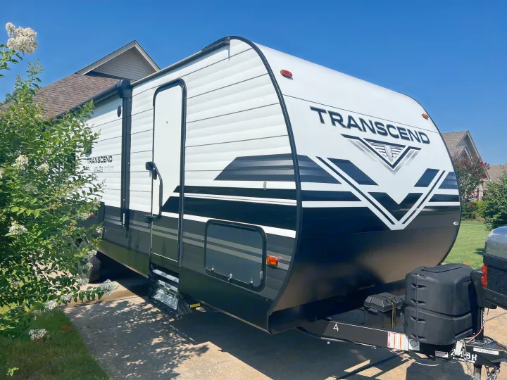 A clean, modern white and black Grand Design Transcend travel trailer, perfect for your next rv rental adventure. Parked outdoors.. Grand Design Transcend 2021