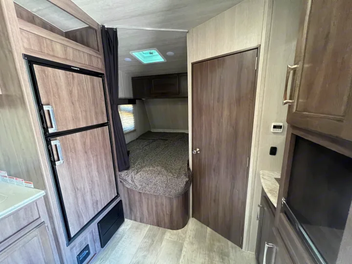 Inside this RV rental: view of bedroom, fridge, and cabinets. A comfy and functional space for travel.. Genesis Supreme Rv Genesis Supreme 2022