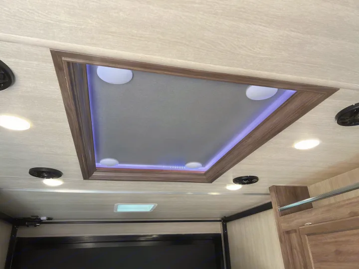 Modern RV rental ceiling showcasing a stylish recessed panel with ambient purple LED lighting, bright white fixtures, and speakers.. Genesis Supreme Rv Genesis Supreme 2022