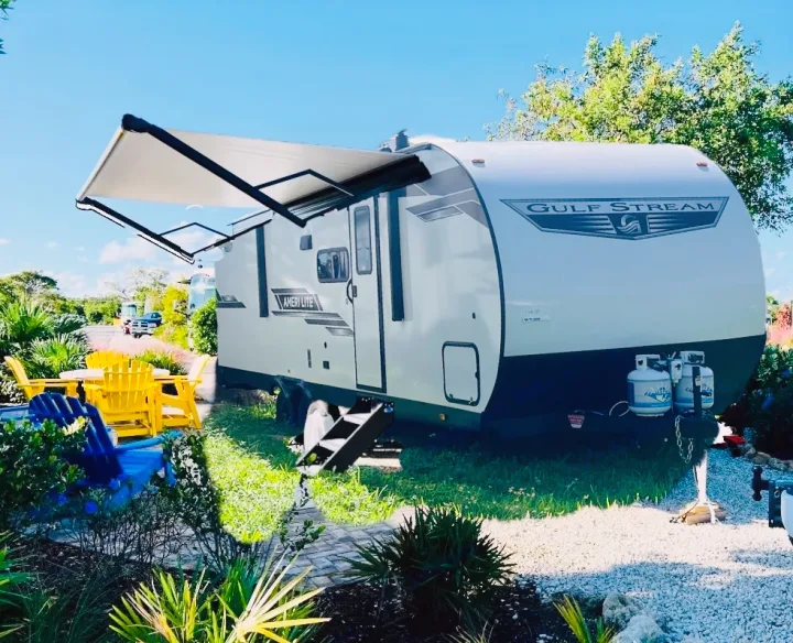 Sunny RV rental: a Gulf Stream travel trailer with extended awning, yellow/blue chairs, and an inviting outdoor setup.. Gulf Stream Ameri-Lite 2024