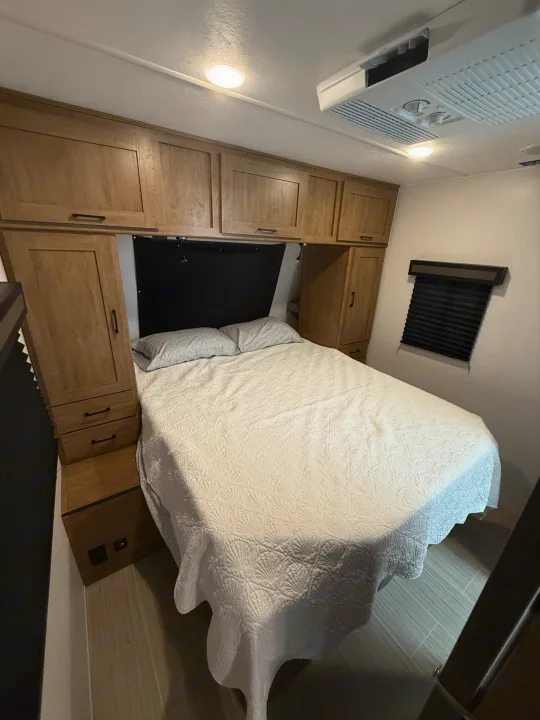 This RV rental features a modern bedroom with a queen bed, wooden cabinets, AC, and window blinds. Ready for your adventure.. Coachmen Express 2024