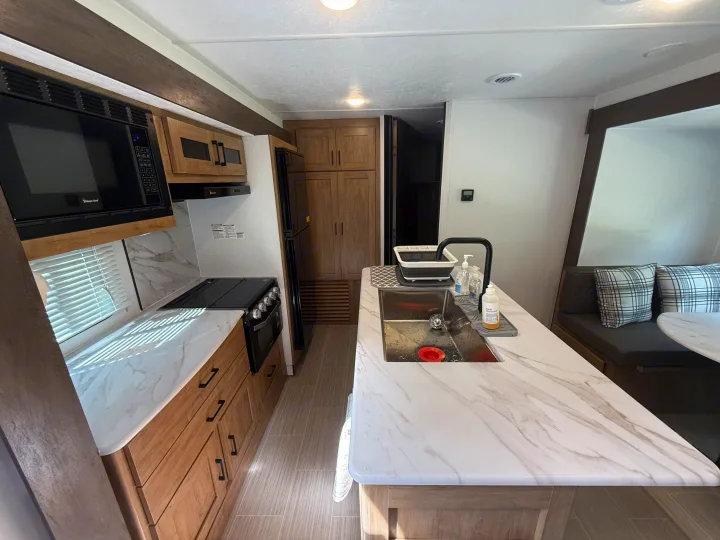 Inside a clean RV rental kitchen with marble-look counters, full appliances, and built-in dining for your adventures.. Coachmen Express 2024