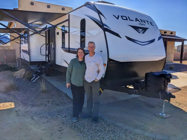 Smiling couple poses with their RV rental, a Volante Lite travel trailer, ready for adventure.. Crossroads RV Volante 2022
