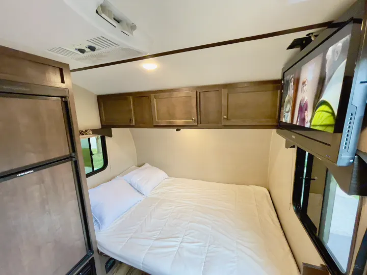 RV rental interior: queen bed, overhead cabinets, AC, fridge, TV. A cozy space for your next road trip adventure!. Sunset Park RV Sun Lite 2019